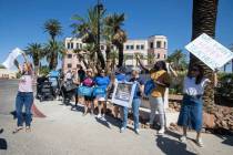 Un grupo de padres y miembros de la comunidad sostienen carteles en apoyo a la mejora salarial ...