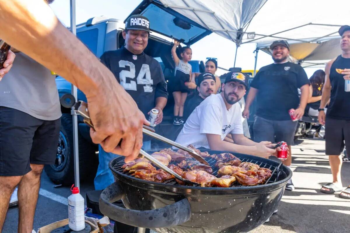 Aficionados de los Raiders asan pollo antes de la primera mitad del partido de la NFL entre los ...