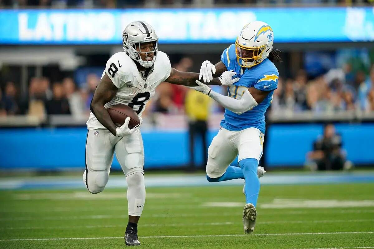 El running back de Los Vegas Raiders Josh Jacobs corre junto al cornerback de Los Angeles Charg ...