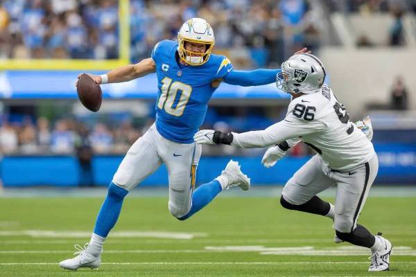 Justin Herbert (12), quarterback de Los Angeles Chargers, se lanza al ataque y arma a Isaac Roc ...