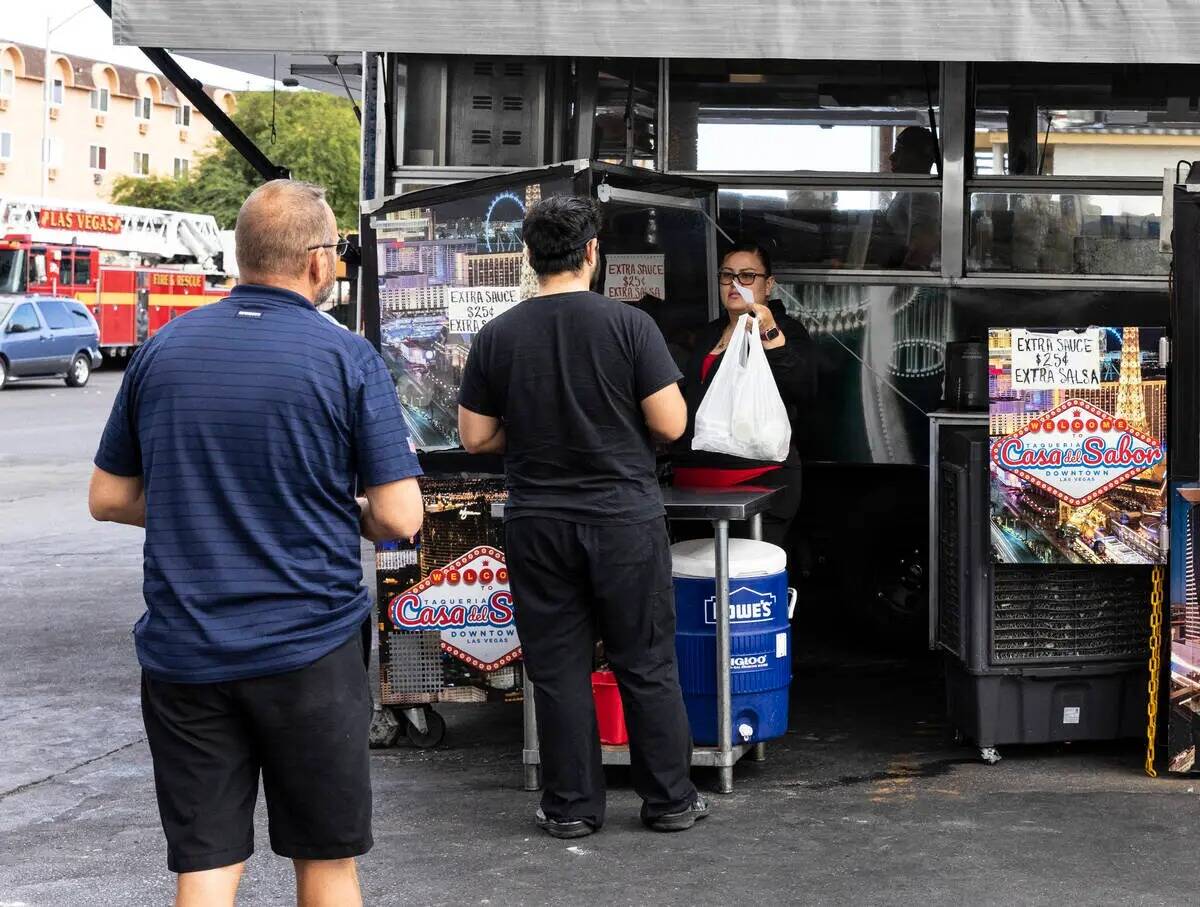 Los clientes esperan en fila para recoger su comida del camión de comida Casa del Sabor en la ...