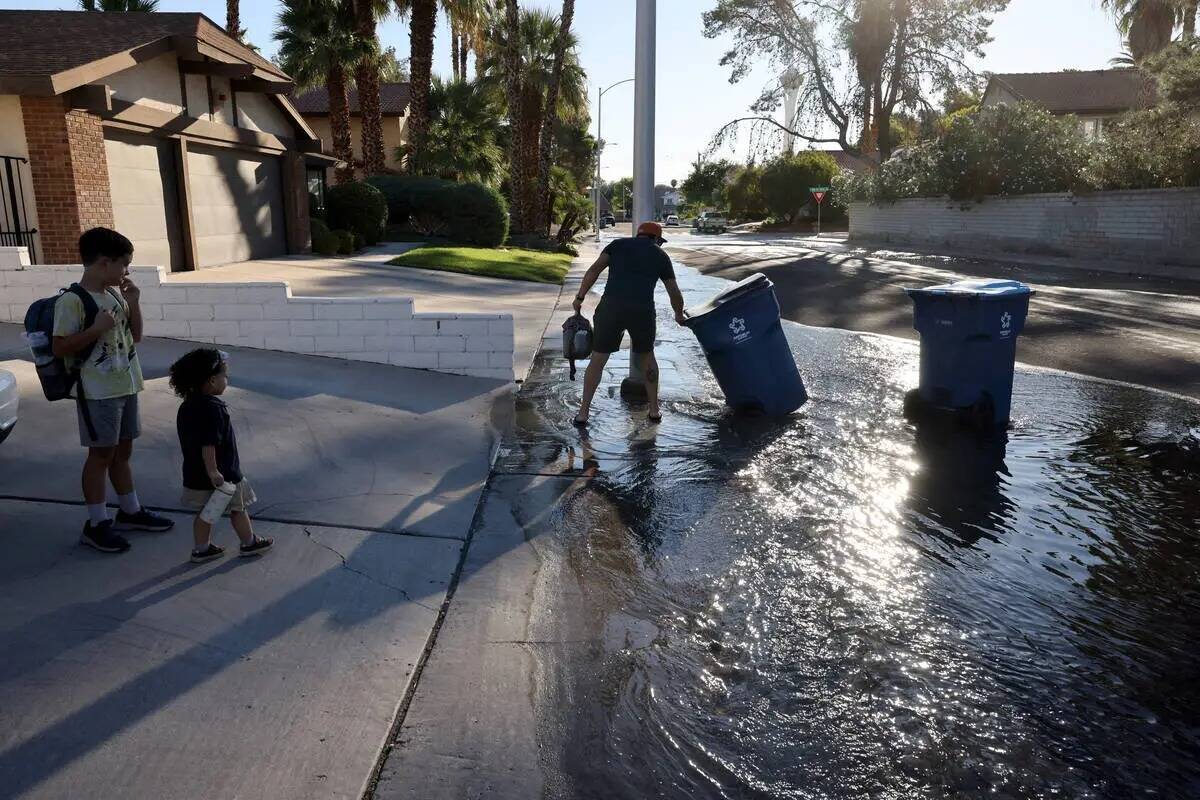 Un residente recupera sus cubos de basura mientras empleados del Distrito de Aguas del valle de ...