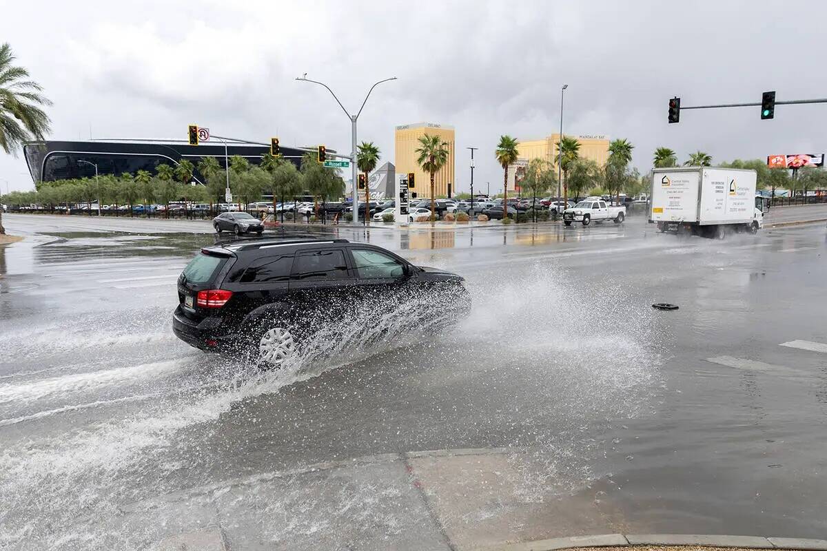 Un vehículo pasa a través de las aguas de la inundación en West Russell Road y Polaris Avenu ...