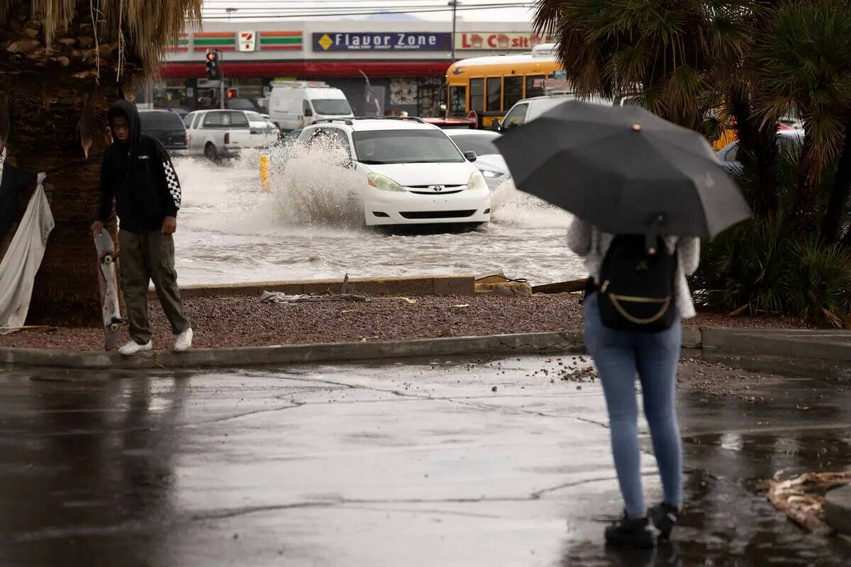 Los peatones se detienen a observar las inundaciones repentinas en la intersección East Sahara ...