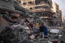Palestinos buscan entre los escombros de un edificio alcanzado por un ataque aéreo israelí, e ...