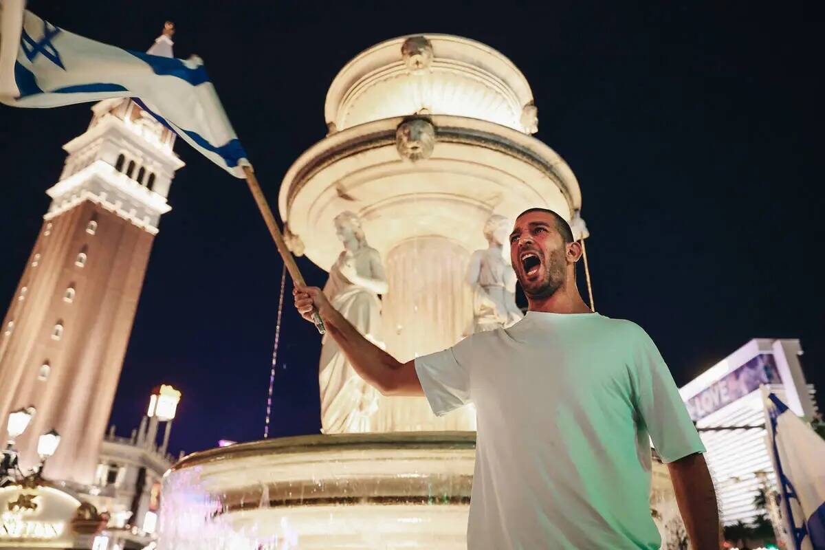 Un hombre sostiene una bandera israelí durante una manifestación pro-Israel frente al Venetia ...