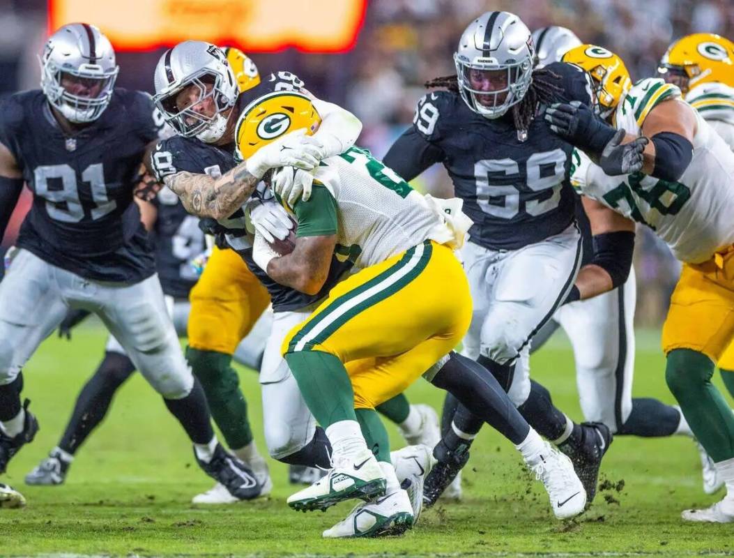 El defensive end de los Raiders Maxx Crosby (98) detiene al running back de los Green Bay Packe ...