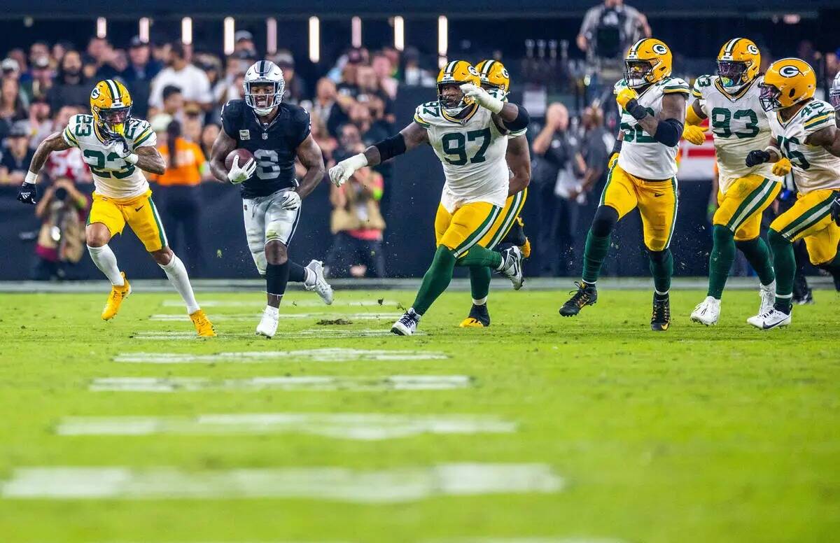 El running back de los Raiders Josh Jacobs (8) se escapa de los defensas de los Green Bay Packe ...