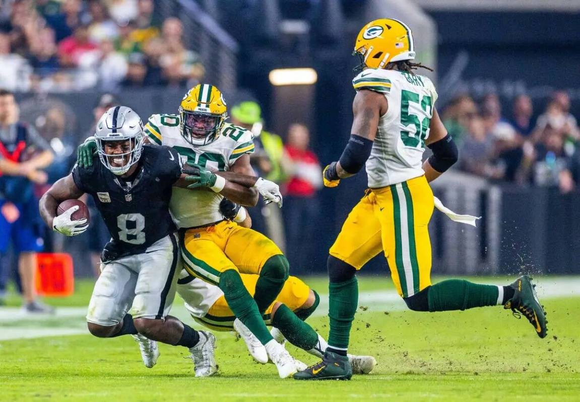 El running back de los Raiders Josh Jacobs (8) es derribado por el safety de los Green Bay Pack ...