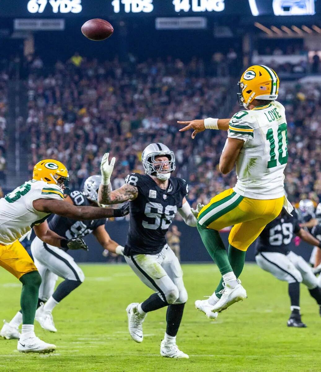 El quarterback de los Green Bay Packers Jordan Love (10) se eleva para pasar por encima de un a ...