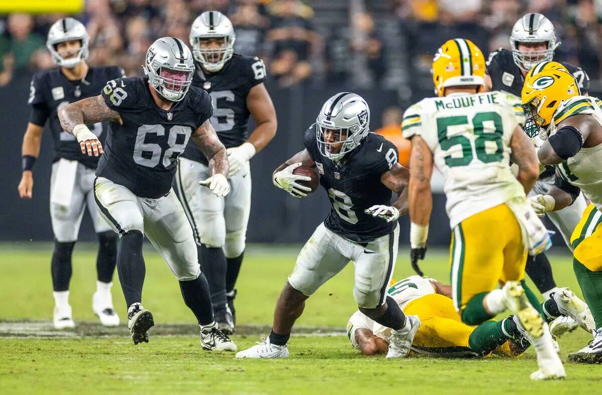 El running back de los Raiders Josh Jacobs (8) corre tras una captura mientras el linebacker de ...