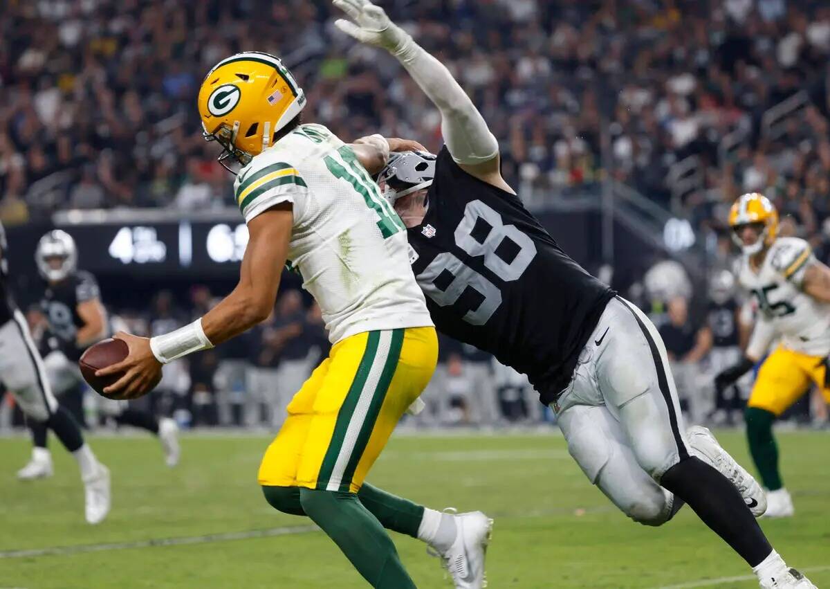 El quarterback de los Green Bay Packers Jordan Love (10) intenta evitar una tacleada del defens ...