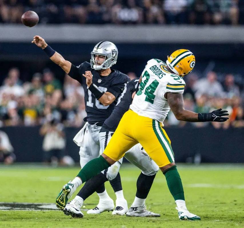 El quarterback de los Raiders Jimmy Garoppolo (10) consigue un pase ante la presión del defens ...