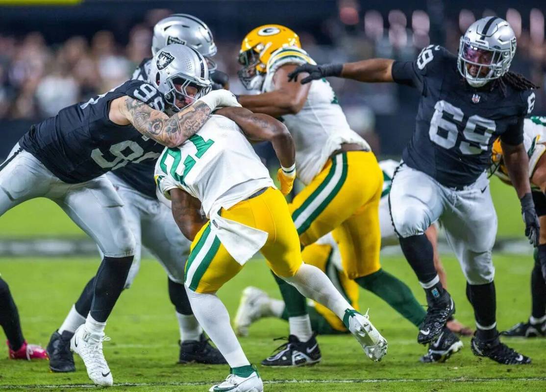 El defensive end de los Raiders Maxx Crosby (98) detiene al running back de los Green Bay Packe ...