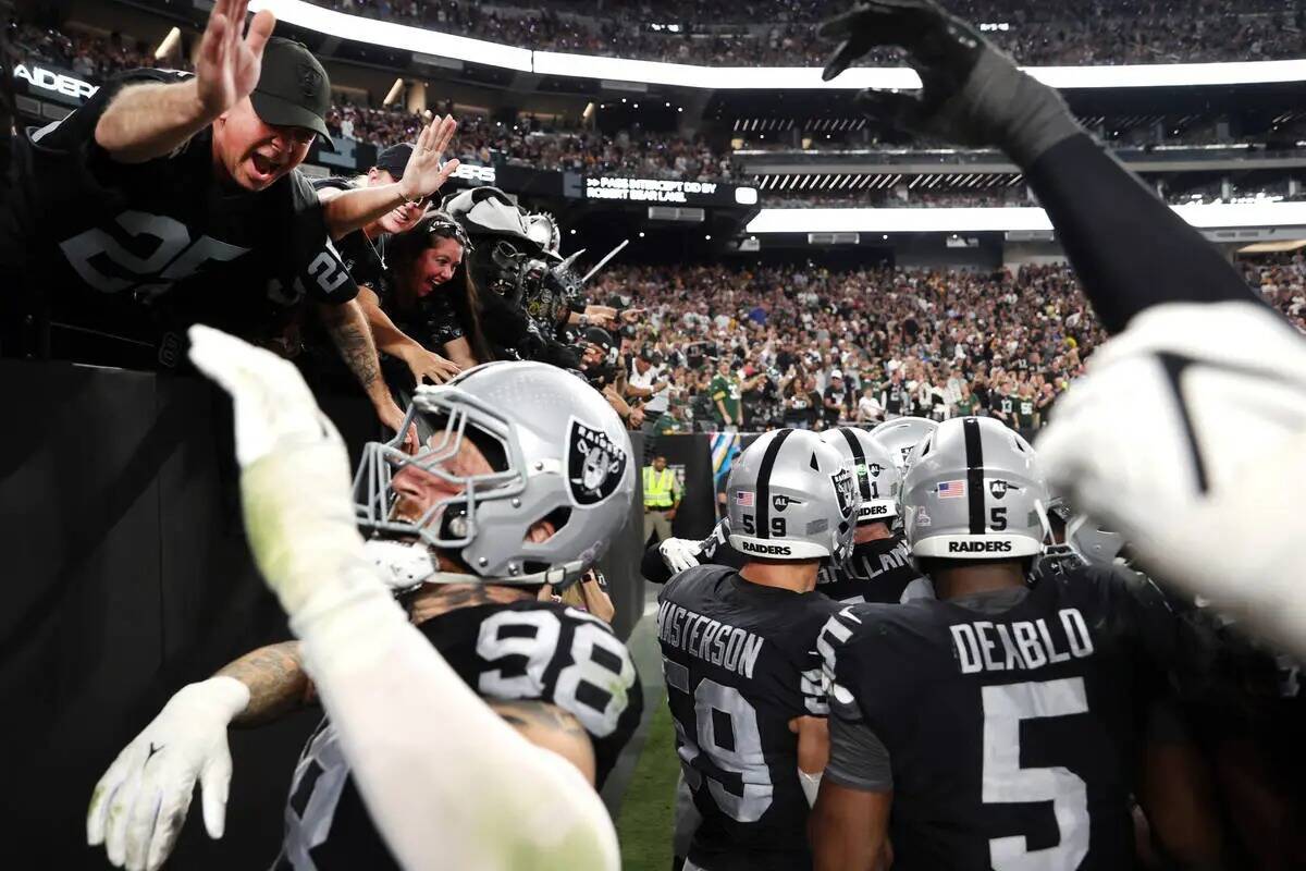 El defensive end de los Raiders Maxx Crosby (98) celebra una intercepción con los fans contra ...