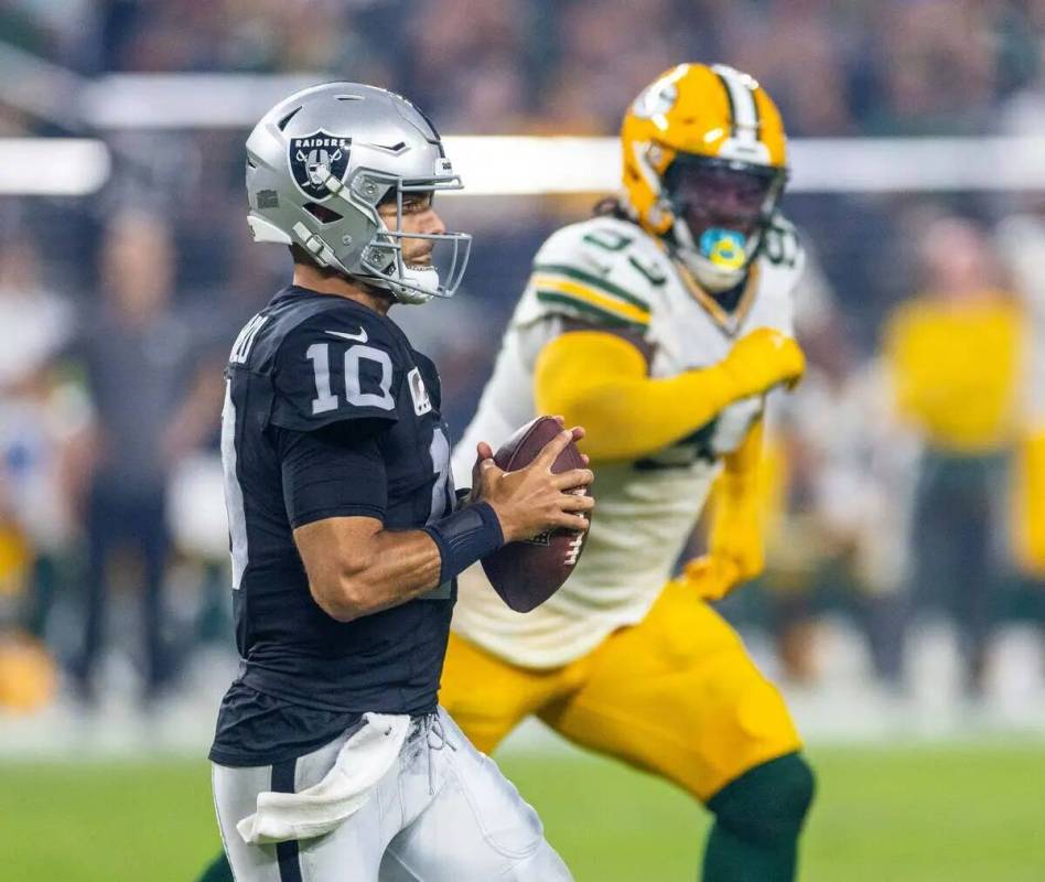 El quarterback de los Raiders Jimmy Garoppolo (10) observa un pase contra la tacleada defensiva ...