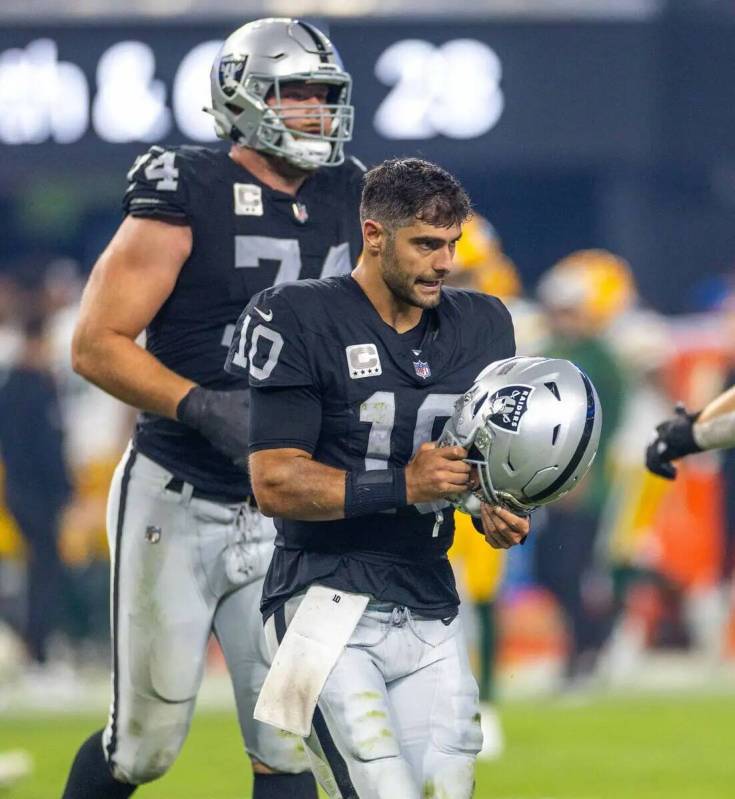 El quarterback de los Raiders Jimmy Garoppolo (10) se libra de un duro sack de la defensa de lo ...