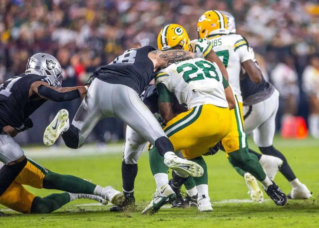 El defensive end de los Raiders Maxx Crosby (98) salta para detener al running back de los Gree ...