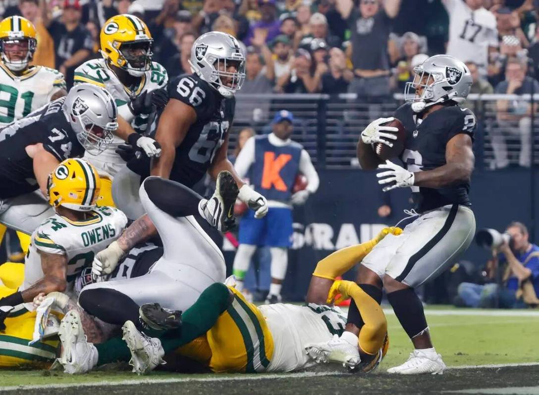 El running back de los Raiders Josh Jacobs (8) rompe las tacleadas del tackle defensivo de los ...