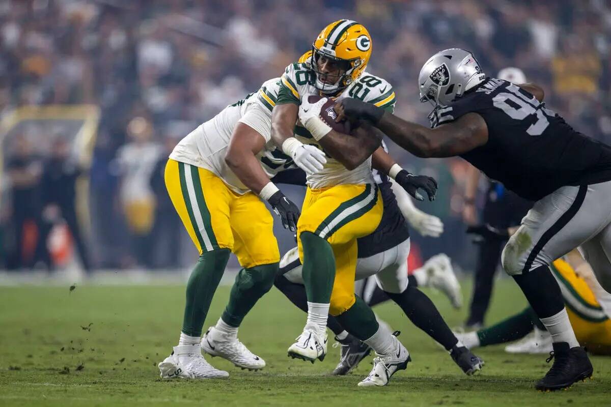 El running back de los Green Bay Packers AJ Dillon (28) intenta pasar a la tacleada defensiva d ...