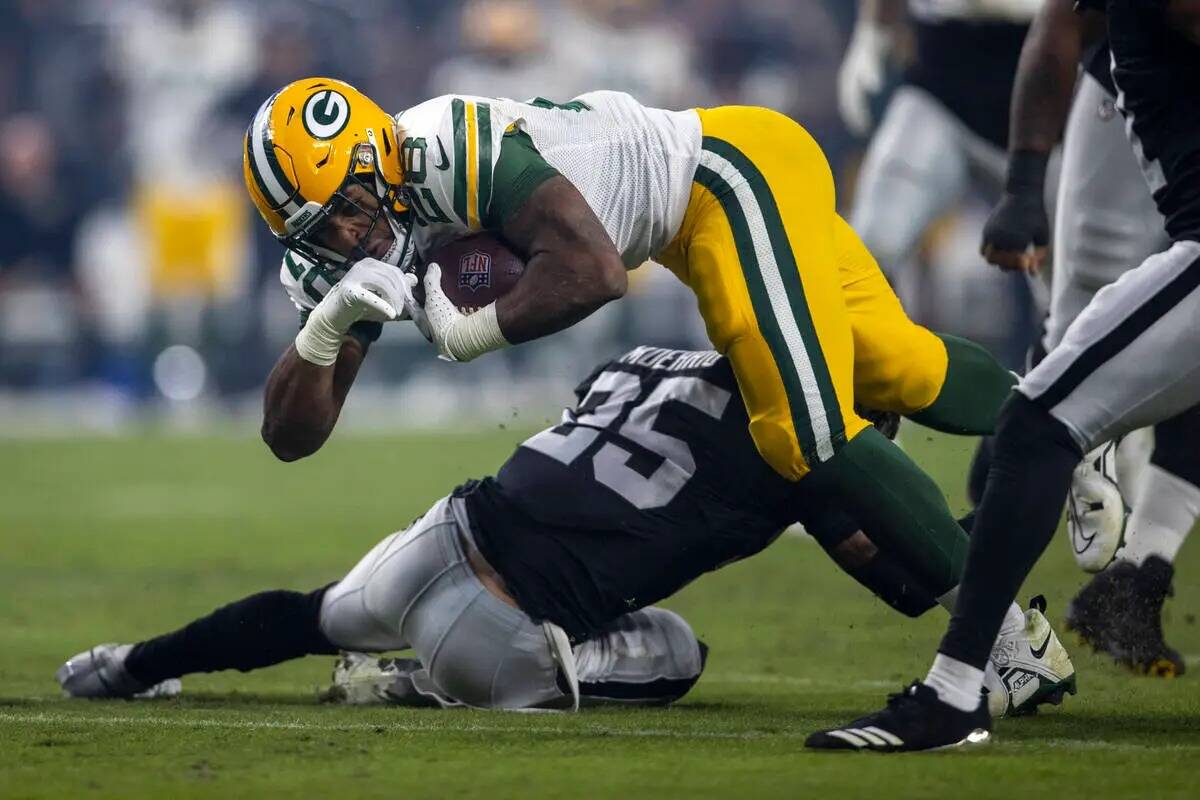 El running back de los Green Bay Packers AJ Dillon (28) es tacleado por el tackle defensivo de ...