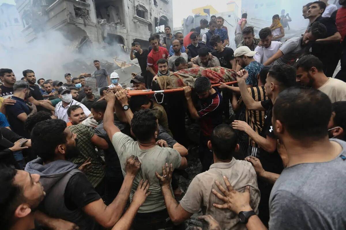 Palestinos retiran un cadáver de los escombros de un edificio tras un ataque aéreo israelí C ...