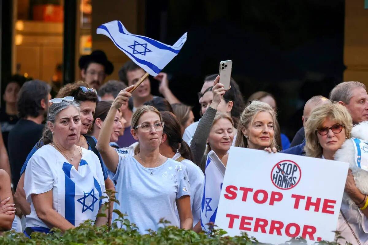 Los asistentes ondean banderas y sostienen carteles junto a miembros de la comunidad judía del ...