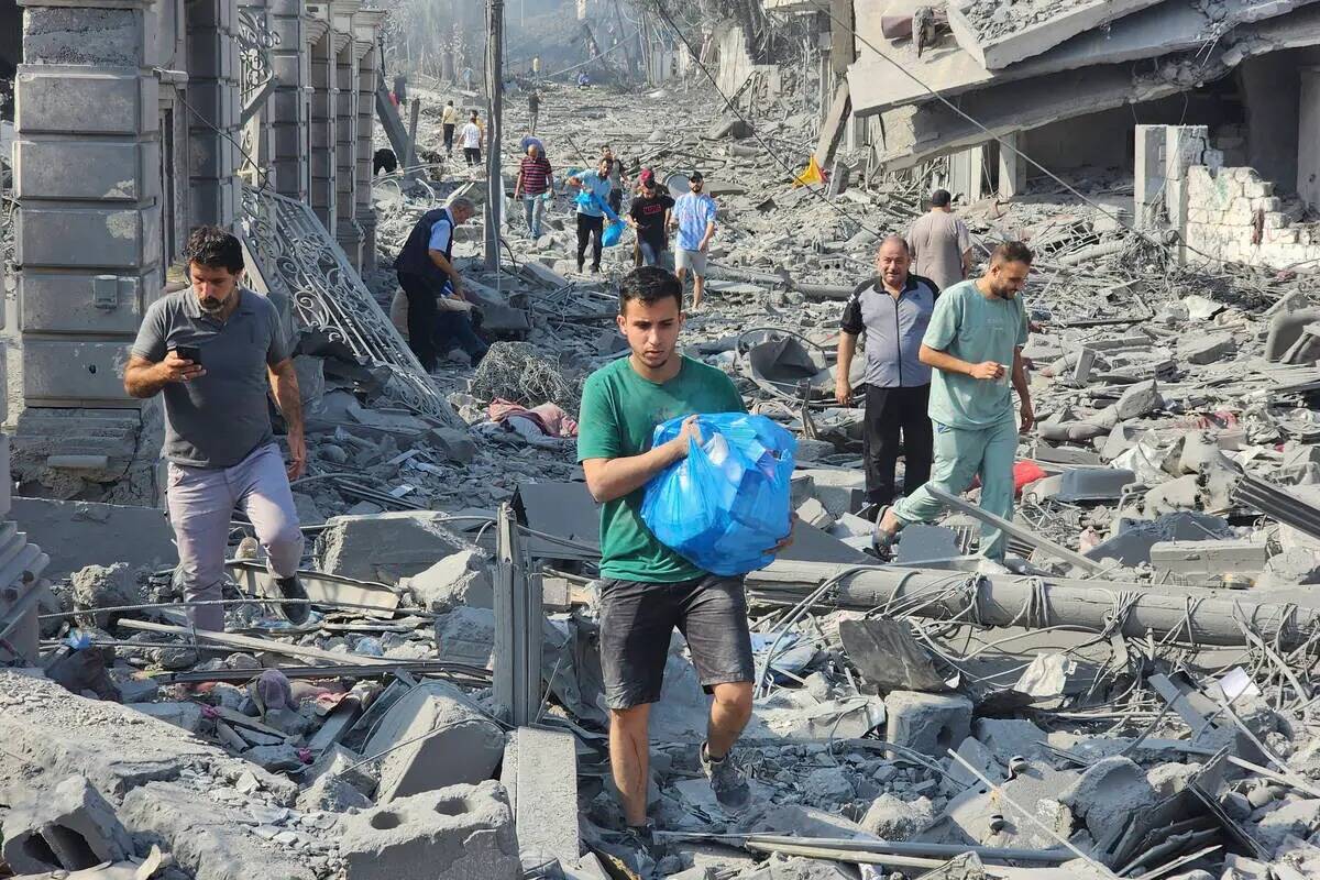 Palestinos caminan entre los escombros de los edificios destruidos por los ataques aéreos isra ...
