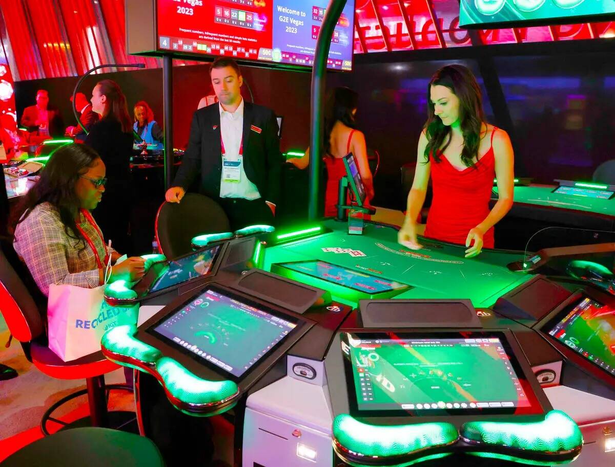Un convencionista juega en la mesa de Blackjack Smart Pit de 5 asientos de Interblock Gaming en ...