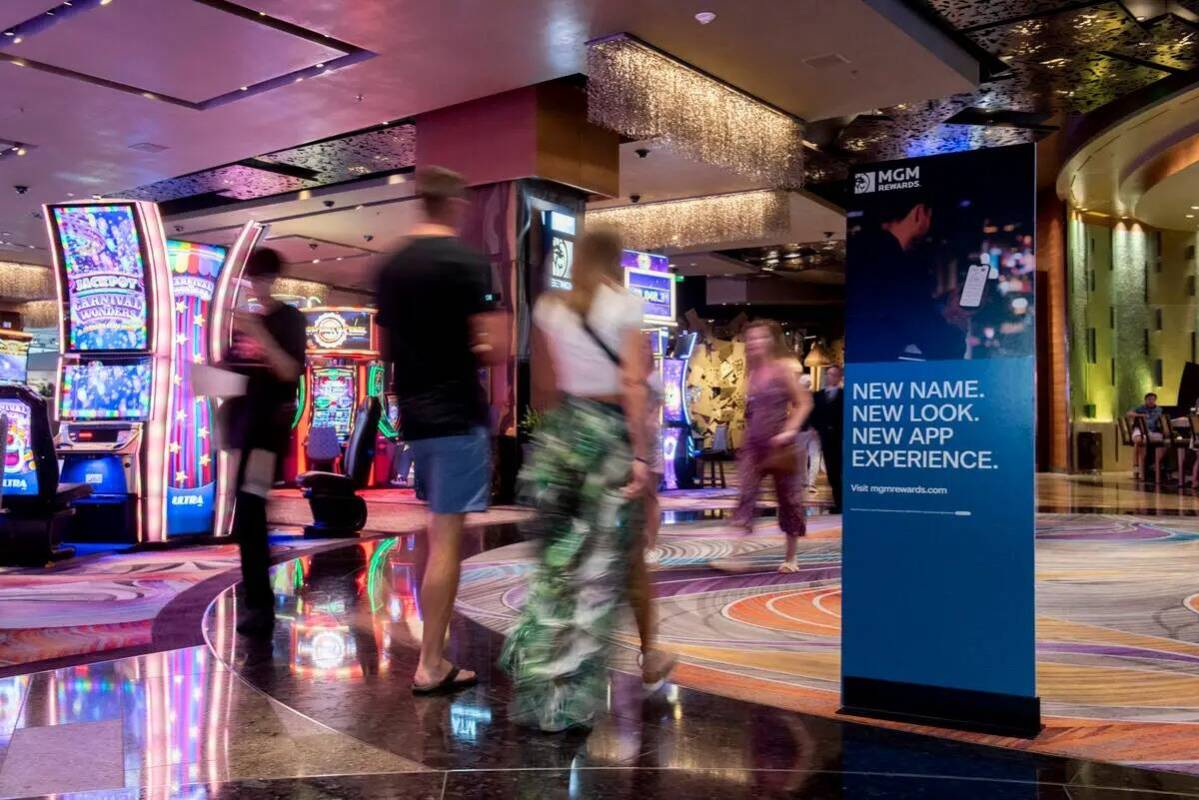 Un grupo de personas pasa junto a carteles que anuncian las ventajas de MGM Rewards en el hotel ...