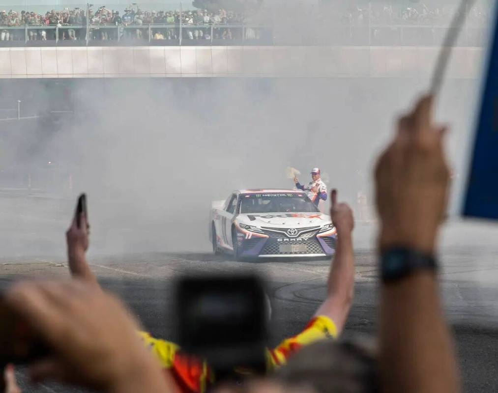 Denny Hamlin saluda a los fanáticos después de hacer un burnout en la intersección de East S ...