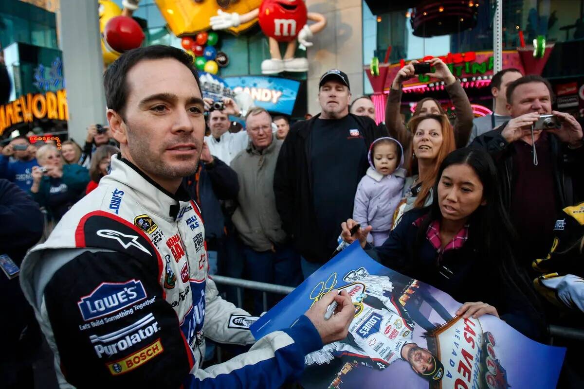 El piloto de NASCAR Jimmie Johnson firma un póster para un fan delante del hotel-casino MGM Gr ...