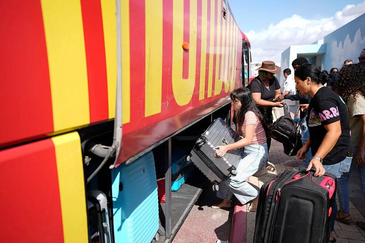 Israelíes cargan sus pertenencias en un autobús mientras evacúan la ciudad de Sderot, en el ...