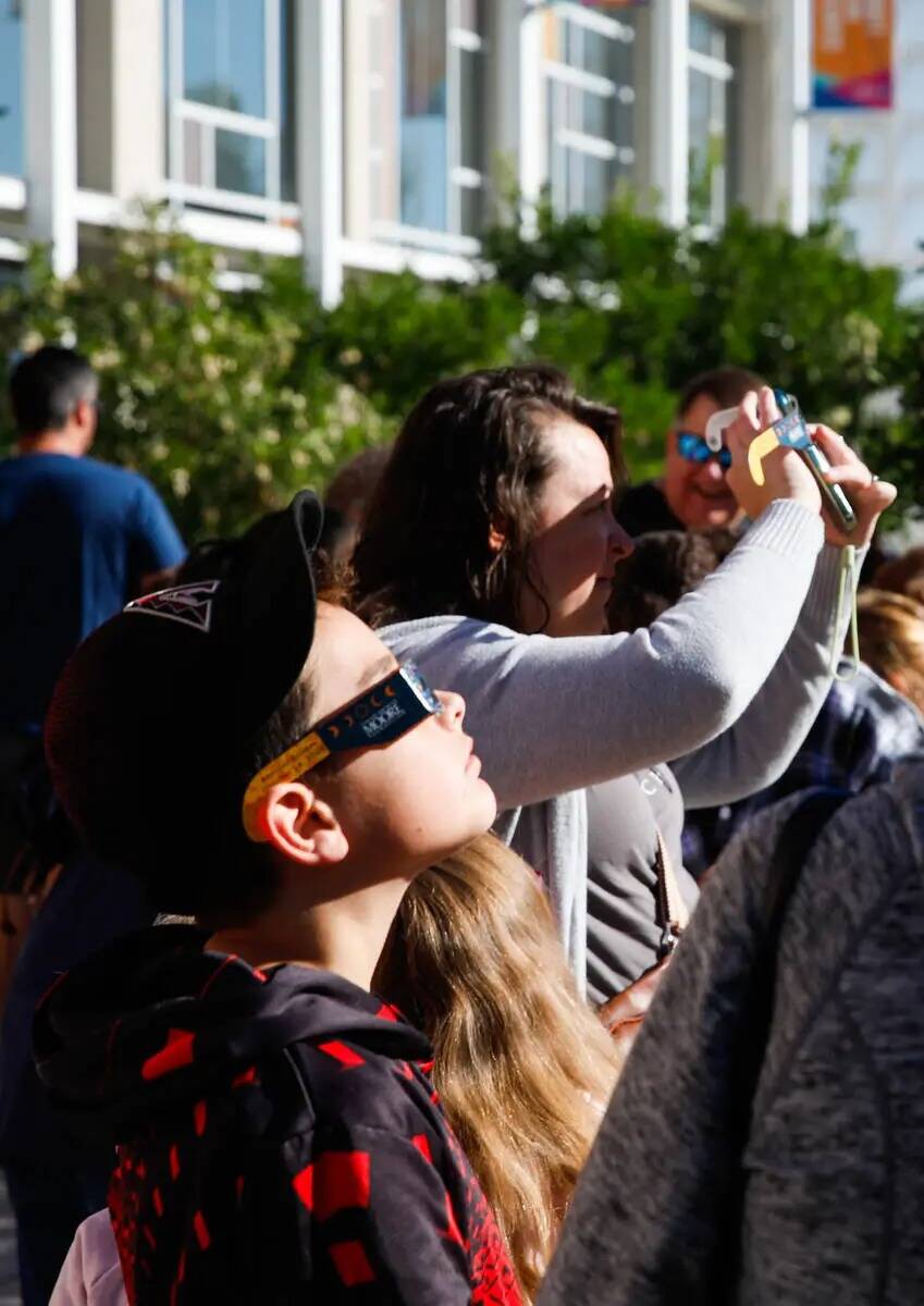 Un grupo de personas observa el eclipse solar anular desde la Centennial Hills Library mientras ...