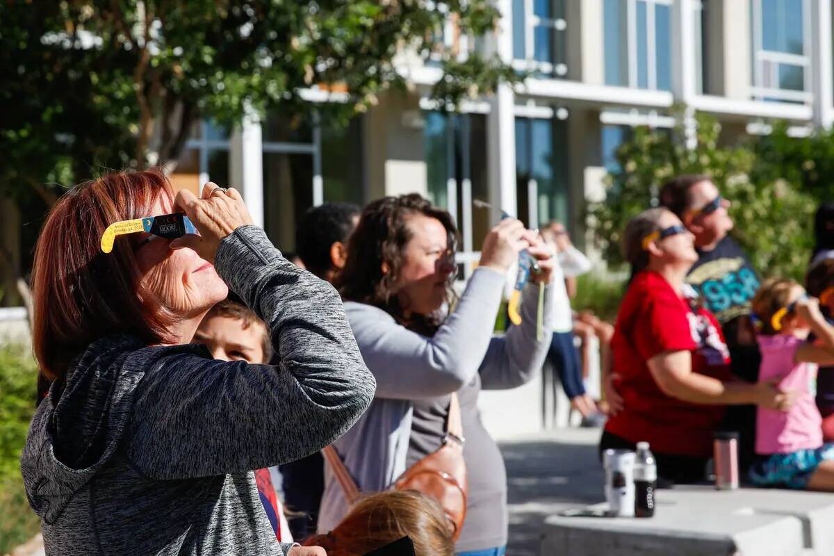 Un grupo de personas observa el eclipse solar anular desde la Centennial Hills Library mientras ...