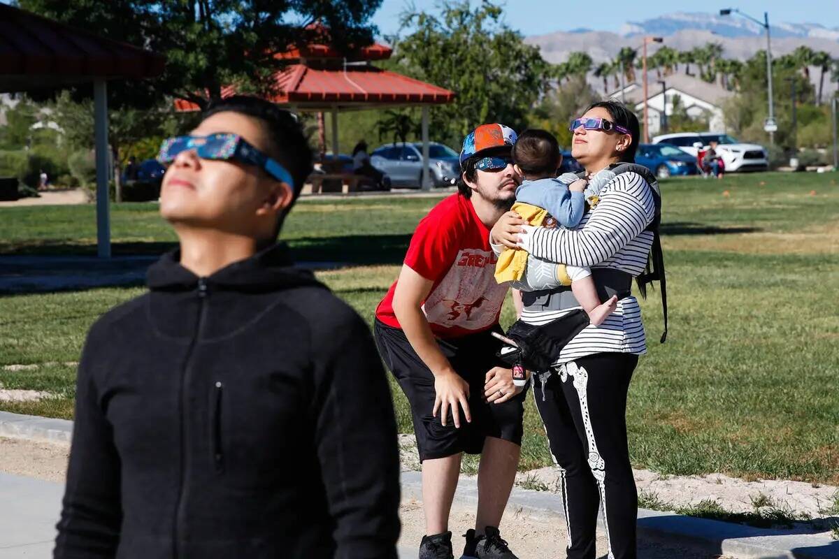 Un grupo de personas observa el eclipse solar anular desde la Centennial Hills Library mientras ...