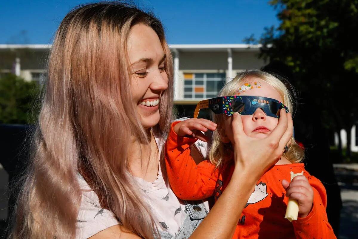 Des Leavitte pone las gafas del eclipse solar a su hijo, Zen Leavitte, mientras contemplan el e ...