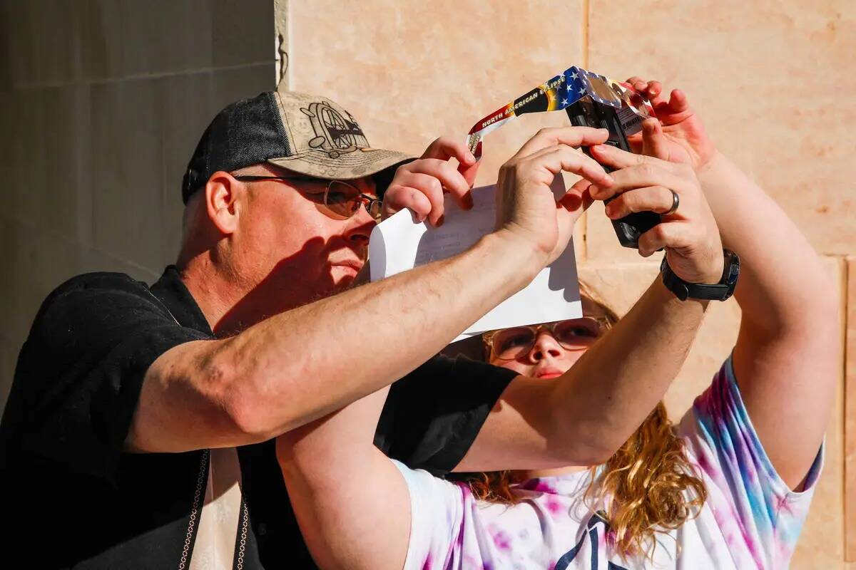 Bruce y Grace Heltzer toman una foto del eclipse solar anular a través de unas gafas especiale ...