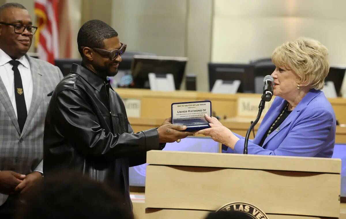 Usher, en el centro, recibe la llave de la ciudad de Las Vegas de manos de la alcaldesa Carolyn ...