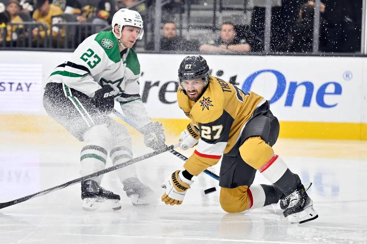 El defensa de los Vegas Golden Knights Shea Theodore (27) mira el puck contra el defensa de los ...