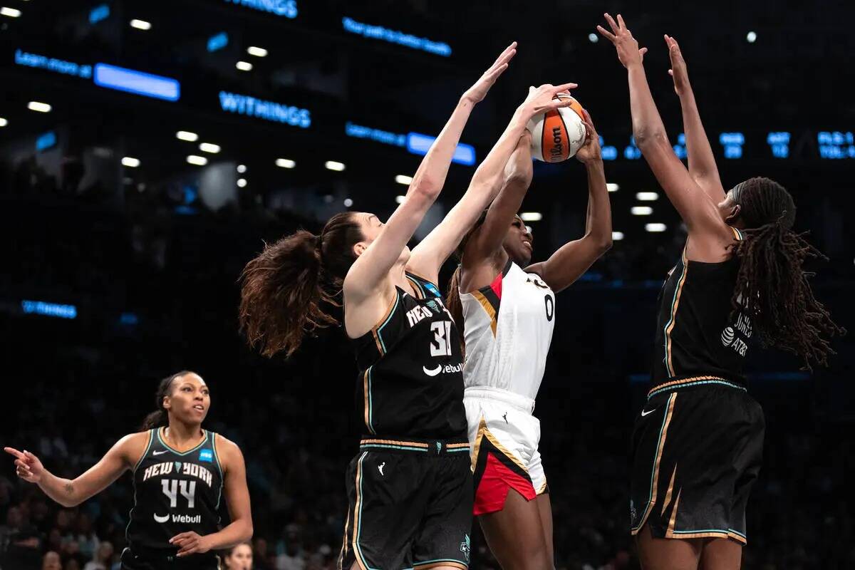 La escolta de Las Vegas Aces Jackie Young (0) intenta pasar entre la alera de New York Liberty ...