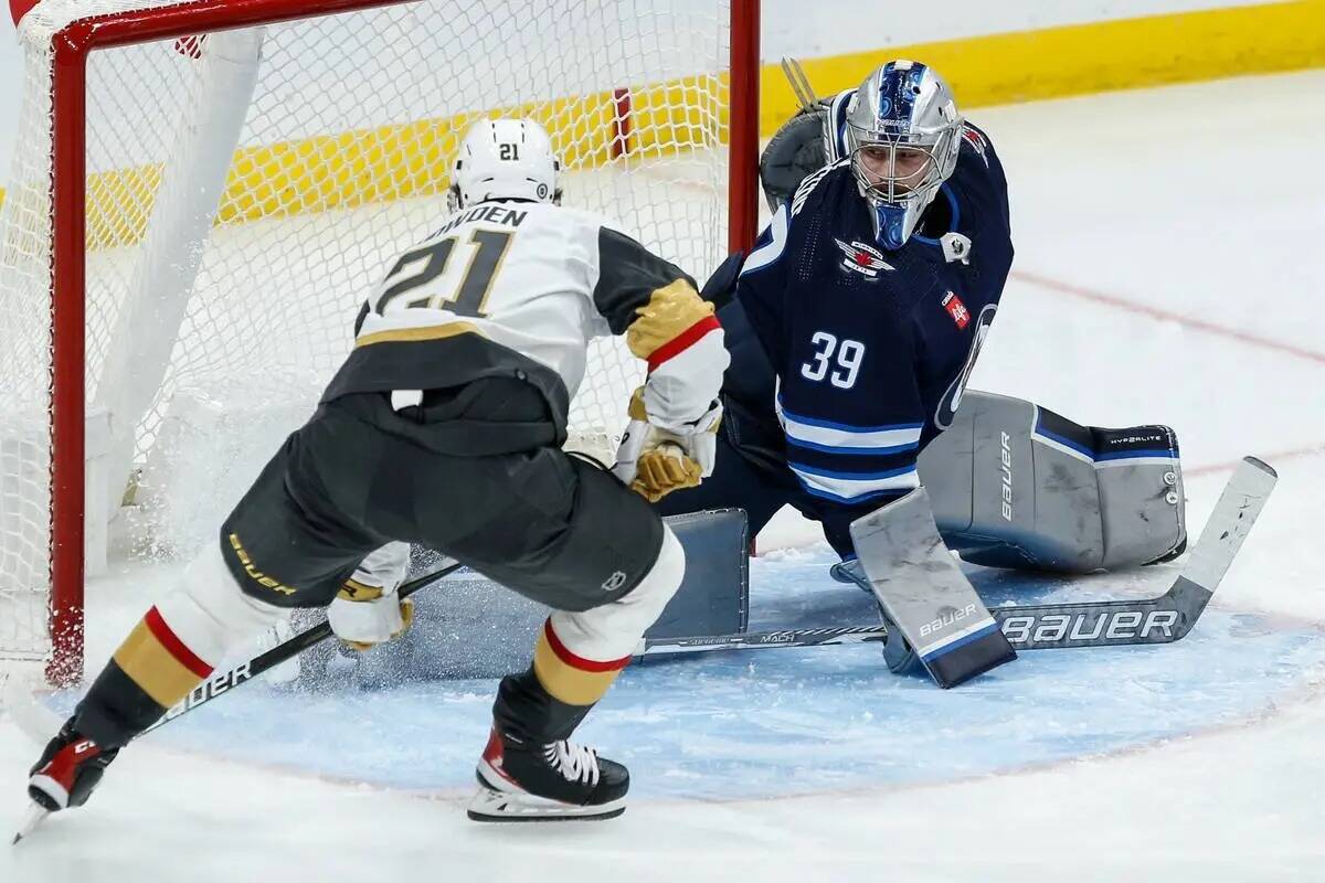 Brett Howden (21) de Vegas Golden Knights anota contra el portero de Winnipeg Jets Laurent Bros ...