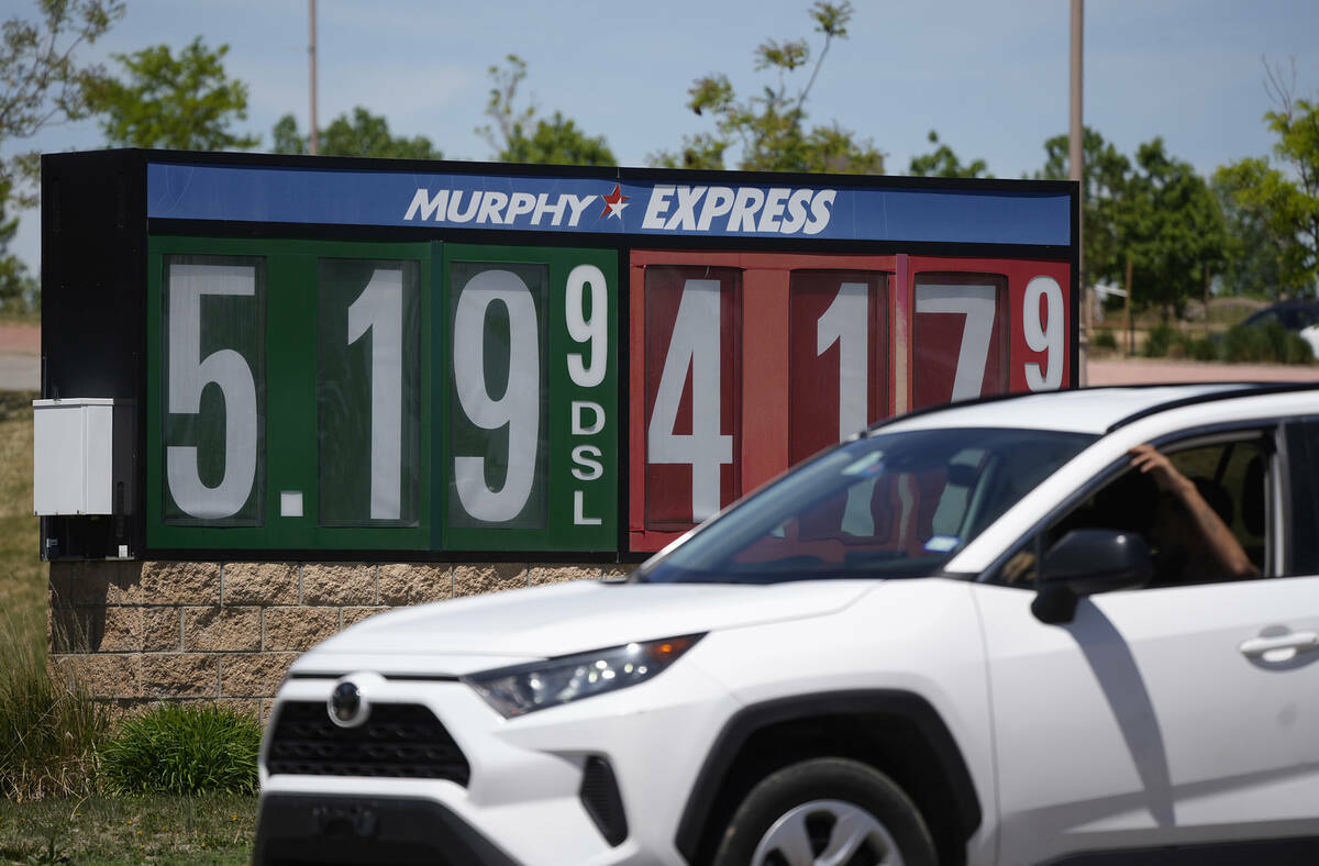 Los precios de la gasolina se muestran afuera de una tienda de conveniencia mientras pasa un au ...