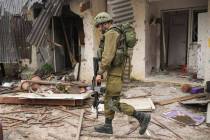 Un soldado israelí pasa junto a una casa dañada durante el ataque de Hamás en el kibutz Kfar ...