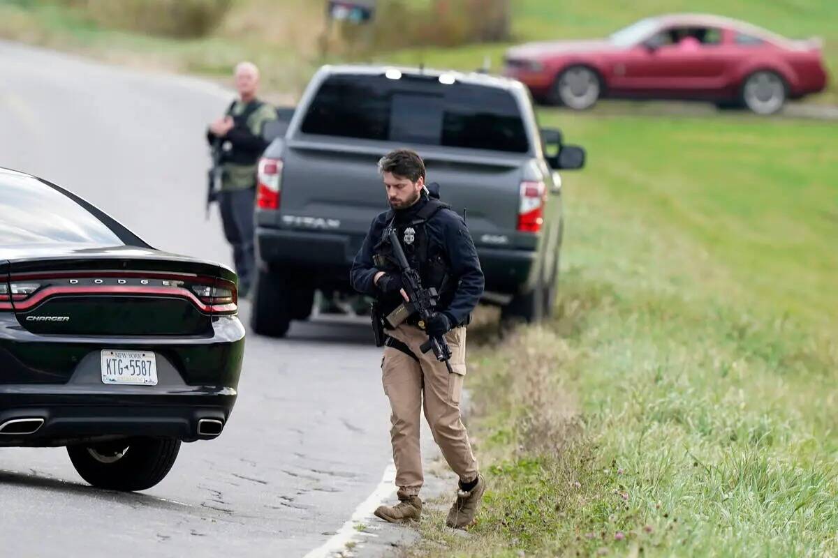 Agentes de la ley sostienen rifles mientras investigan una escena, en Bowdoin, Maine, jueves 26 ...