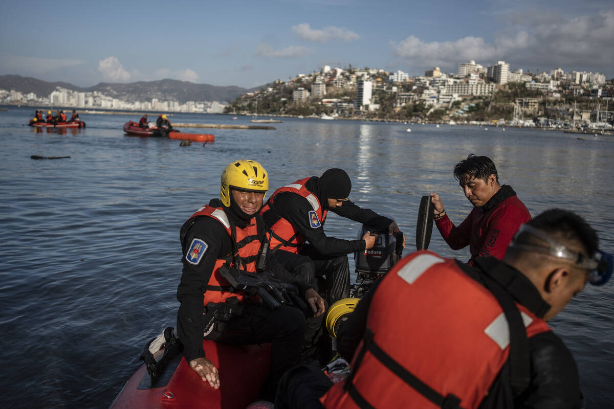 Firefighters and scuba divers search for bodies near sunken boats at a yacht club in Acapulco, ...