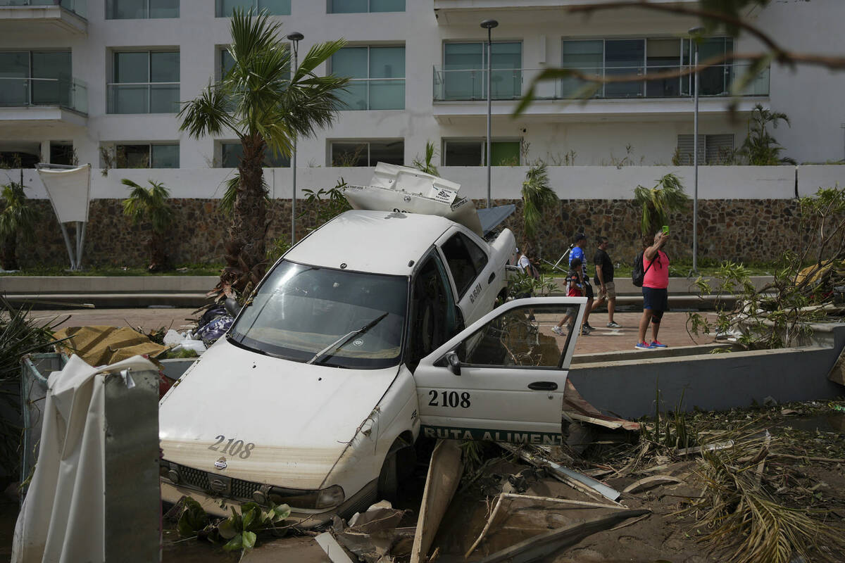 Un auto dañado yace en un separador de la calle después de que el huracán Otis arrasara Acap ...