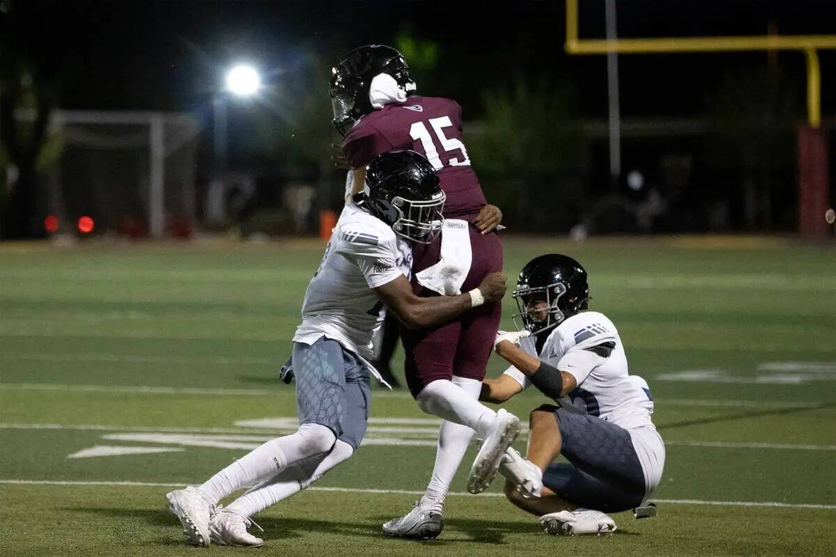 El linebacker de Desert Pines Semauri Norris-Johnson, izquierda, taclea al quarterback de Faith ...