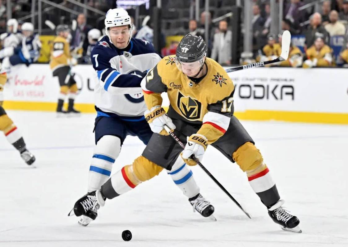 El defensa de los Vegas Golden Knights Ben Hutton (17) maneja el puck contra el centro de los W ...