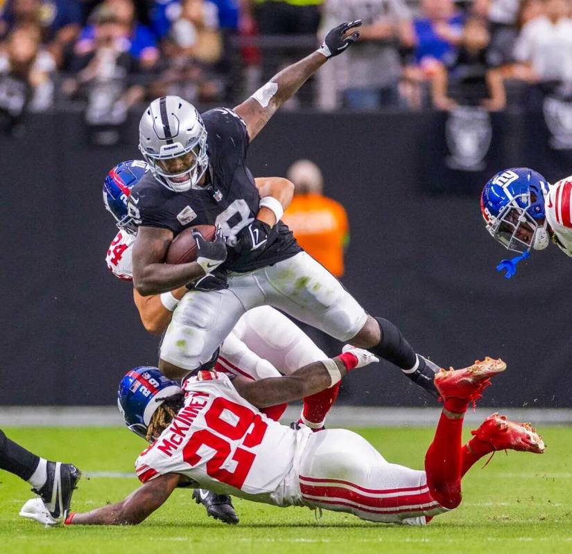 El running back de los Raiders Josh Jacobs (8) es tomado por el safety de los New York Giants D ...